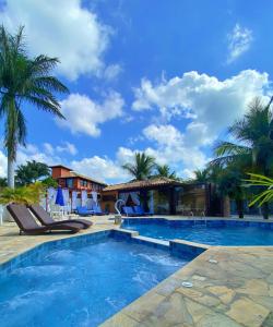 a swimming pool with palm trees and a house at Villa Baobá Pousada & Spa in Búzios