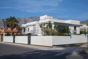 a white house with palm trees in front of a mountain at Tra Le Braccia di Morfeo in Terrasini
