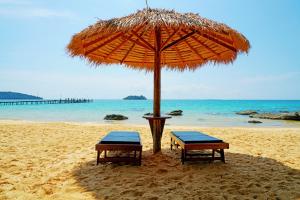 two chairs under an umbrella on a beach at Tree House Bungalows in Koh Rong Island