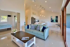 a living room with a blue couch and a table at Heliconia Grove - 1 bedroom - on Hamilton Island by HIHA in Hamilton Island +25 photos