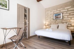 ein Schlafzimmer mit einem Bett, einem Tisch und einem Stuhl in der Unterkunft Les Secrets de Sainte Eulalie - Première Conciergerie in Montpellier