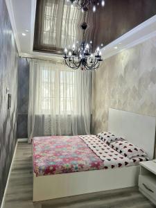 タシュケントにあるCozy New Apartment in a Quite Neighborhoodのベッドとシャンデリアのある寝室