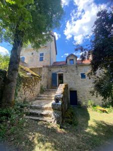 an old stone building with a blue door and stairs at La Combe aux étoiles in Villefranche-de-Rouergue