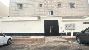a white building with a black door in front of it at شقة جديدة ثلاث غرف نوم داخل حدود الحرم in Al Madinah