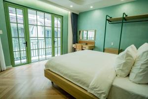 a bedroom with a white bed with green walls and windows at Biệt thự sân vườn sang trọng Hayha Villa - Tropical Garden Khem Beach in Phu Quoc