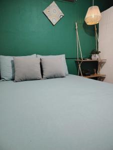 a bedroom with a white bed with a green wall at Pacific Room El Tunco Surf City in Tamanique +14 photos
