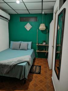a bedroom with a bed with a green wall at Pacific Room El Tunco Surf City in Tamanique