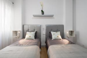 2 camas en una habitación con paredes blancas en MalagaSuite City Center Ollerías, en Málaga