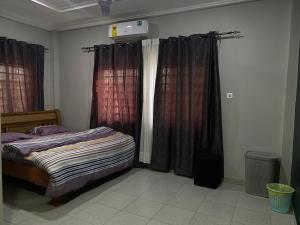 a bedroom with a bed and two windows with curtains at Bel's Place in Trofwi