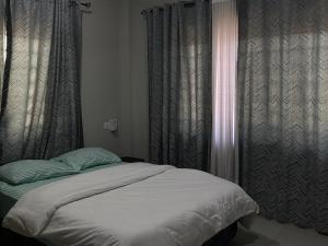 a bed in a bedroom with curtains and a window at Bel's Place in Trofwi +5 photos