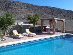 una piscina con 2 sillas y un cenador en Casa Panorama, en Mazarrón