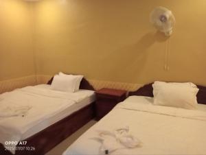two beds in a small room with white sheets at Chomno Prekampil guesthouse in Phumĭ Prêk Chrey