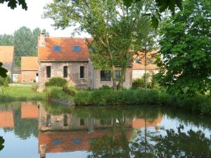 una vecchia casa si riflette in uno specchio d'acqua di Paardenhof Guesthouse a Esquelbecq