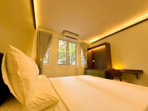 a bedroom with a bed and a desk and a window at Bamboura Home in Hanoi