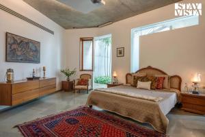 アリバグにあるStayVista at Villa Ekanta with BBQのベッドと大きな窓のある寝室