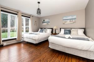 two beds in a room with wood floors and windows at Chalet in the Woods, Serenity in Saint Come