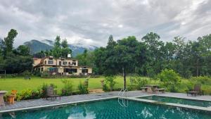 a swimming pool with a house in the background at Hideaway By Aahma in Rāmnagar