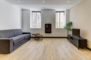 a living room with a couch and a television at La manufacture - Centre ville - 3 étoiles in Bourg-en-Bresse +10 photos