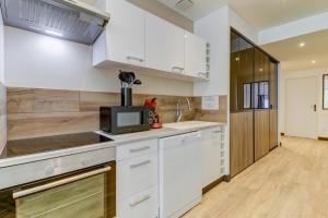 a kitchen with white cabinets and a microwave at La manufacture - Centre ville - 3 étoiles in Bourg-en-Bresse