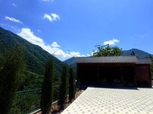 a building with trees and mountains in the background at AGA HOTEL & Restaurant in Haghpat