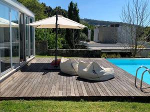 eine Holzterrasse mit Sonnenschirm neben einem Swimmingpool in der Unterkunft Lovely Caminha Villa 3 Bedrooms Villa Lilac Private Pool in Caminha