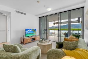 a living room with a couch and a tv at Belle Escapes 14 Harbour Lights with tranquil ocean views in Cairns