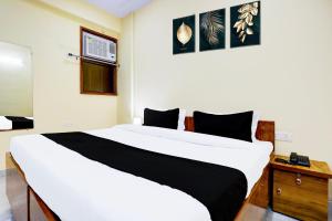 a bedroom with a large white bed and a wooden dresser at Hotel O Mother Touch in Indirapuram