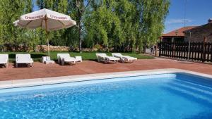 uma piscina com guarda-sol e cadeiras em Finca Los Caleros em Juan Gallegos