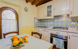 a kitchen with a table with a bowl of fruit on it at Olivo Cottage - Monti 1824 in Casole dʼElsa
