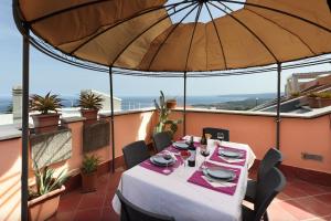 a table on a balcony with an umbrella at Taormina center 4 BR penthouse, terrace with views in Taormina