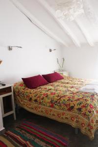 1 cama con almohadas rojas en una habitación blanca en Casa Baraka, en Algodonales