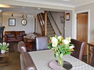 a living room with a table with a vase of flowers at Llys Aled in Llanedwen