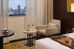 a hotel room with a chair and a bed and a window at BaoHua Harbour View Hotel in Haikou
