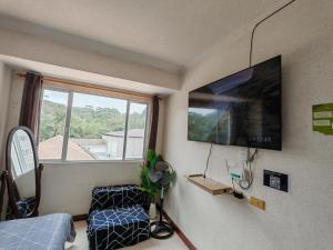 ein Zimmer mit Fernseher, Stuhl und Fenster in der Unterkunft Mountain Breeze in Baguio City