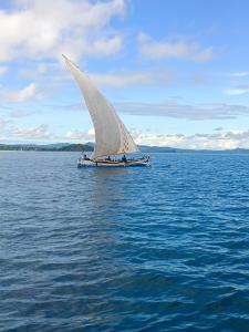 a boat with a white sail in the water at La Maison de Morgana in Bemoko