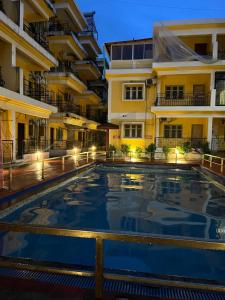 una piscina de hotel frente a los edificios por la noche en Sorted Stays, en Calangute
