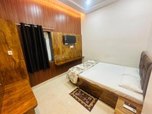 ein kleines Schlafzimmer mit einem Bett und einem Fernseher in der Unterkunft Radhe Krishna Homestay in Varanasi