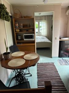 a kitchen with a table and a room with a bed at Namiņš in Ragaciems