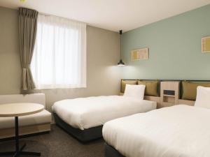 a hotel room with two beds and a table at Comfort Hotel Mito in Mito