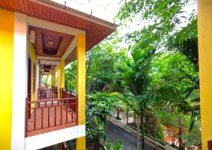 a yellow house with a balcony and trees at NanaSky Kampot Residence 