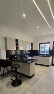 a large kitchen with a black counter and a stool at Le luxe MENZAH5 in Ariana