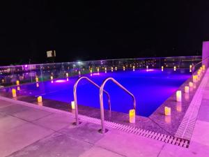 a swimming pool lit up with purple lights at night at Hotel Shemron in Gugal Kota
