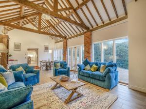 a living room with blue couches and a table at Stable End in Whitchurch