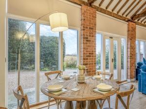 a dining room with a table and chairs and windows at Stable End in Whitchurch