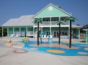 a playground in front of a large building with a house at BB47 - A Wave From It All in Kill Devil Hills