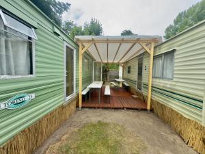 梅尔诺SummerCamp Domki Holenderskie Centrum Mielno 200m do Morza的带顶棚的绿色拖车门廊，配有野餐桌