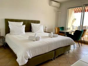 a bedroom with a large white bed with a table and chairs at Mansfield vue carte Postale Terrasse Piscine calme port à 200m à pied in Menton