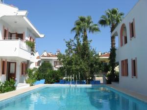 a swimming pool in front of a house with palm trees at Flower Villa Apart in Kemer
