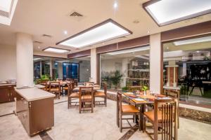 un ristorante con tavoli, sedie e finestre di Prakruti Resort a Vadodara