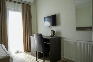 a room with a desk with a chair and a television at Hotel BABU in Kutaisi